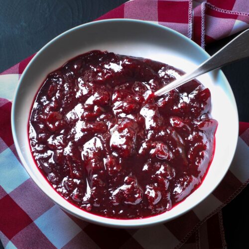 cranberry sauce in a white bowl with a spoon.