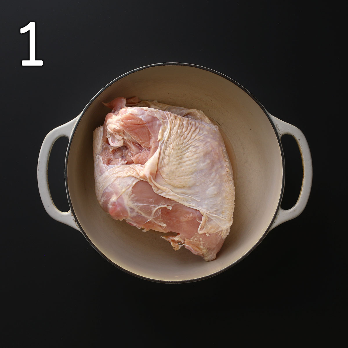 turkey breast on its side in a beige dutch oven.