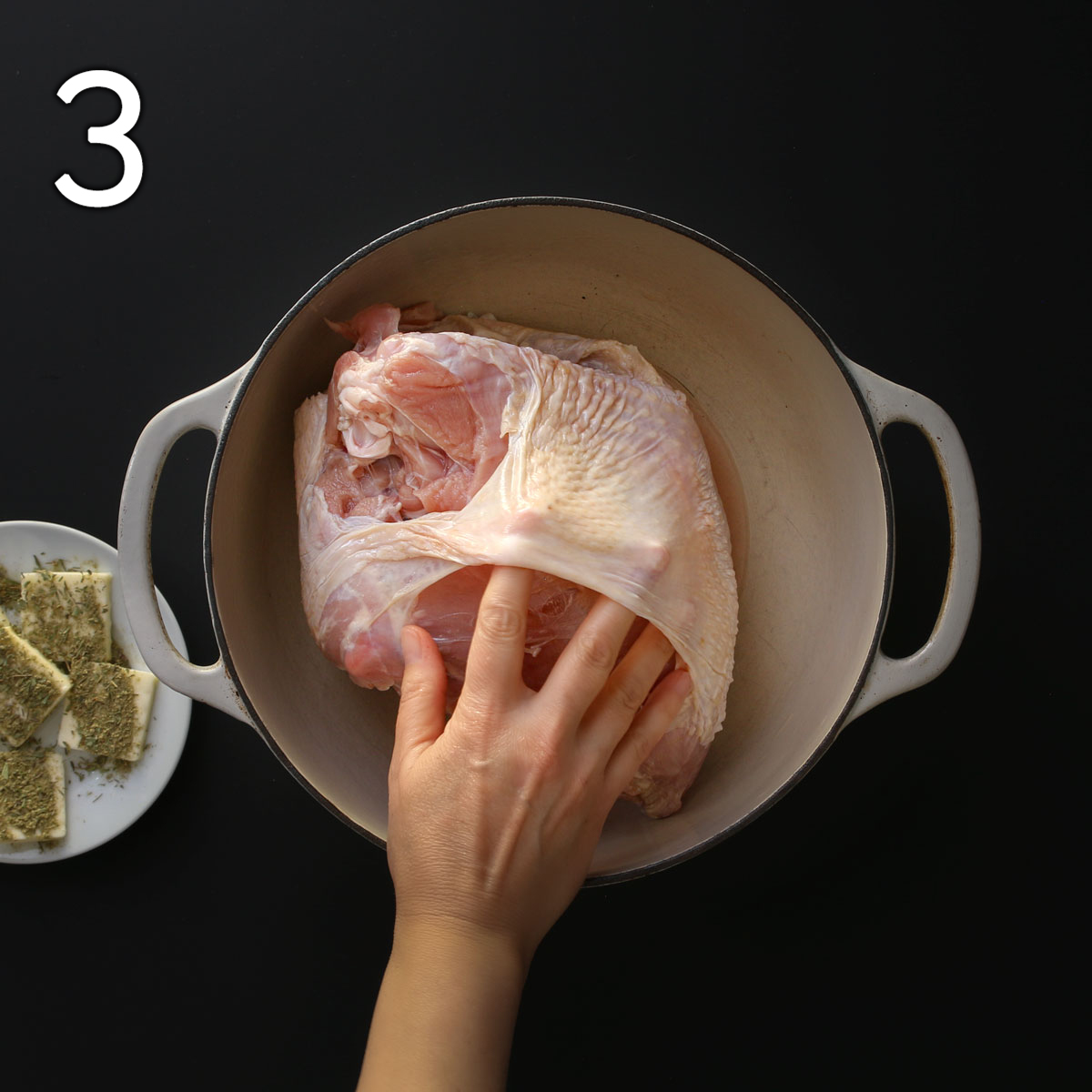hand loosening the skin on the turkey breast.