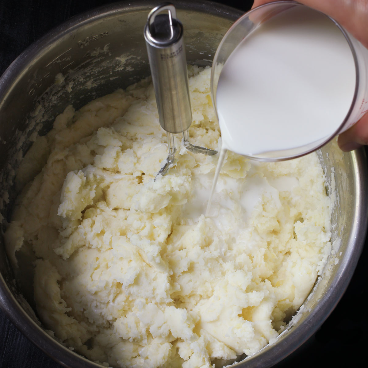 adding cream to the mashed potatoes for the casserole.