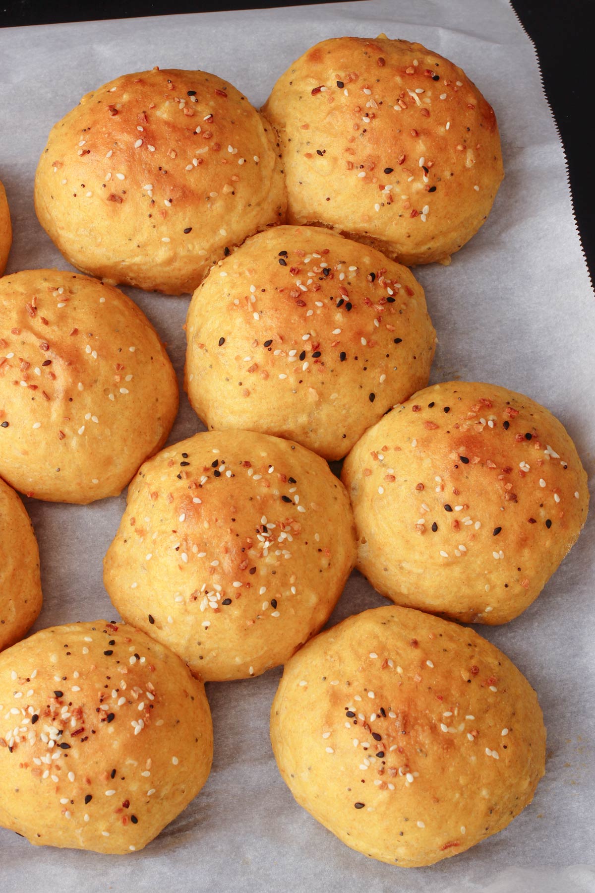 baked pumpkin dinner rolls on parchment paper.