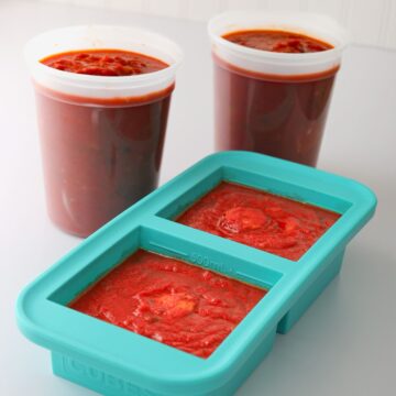 two tubs of spaghetti sauce next to souper cube of sauce.