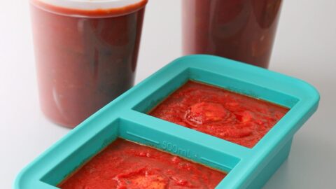 two tubs of spaghetti sauce next to souper cube of sauce.
