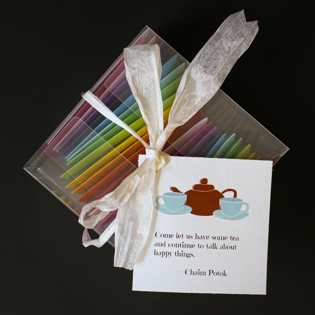 colored envelopes in a clear plastic box, tied with a white bow and a tea quote card on top, for a tea advent calendar.