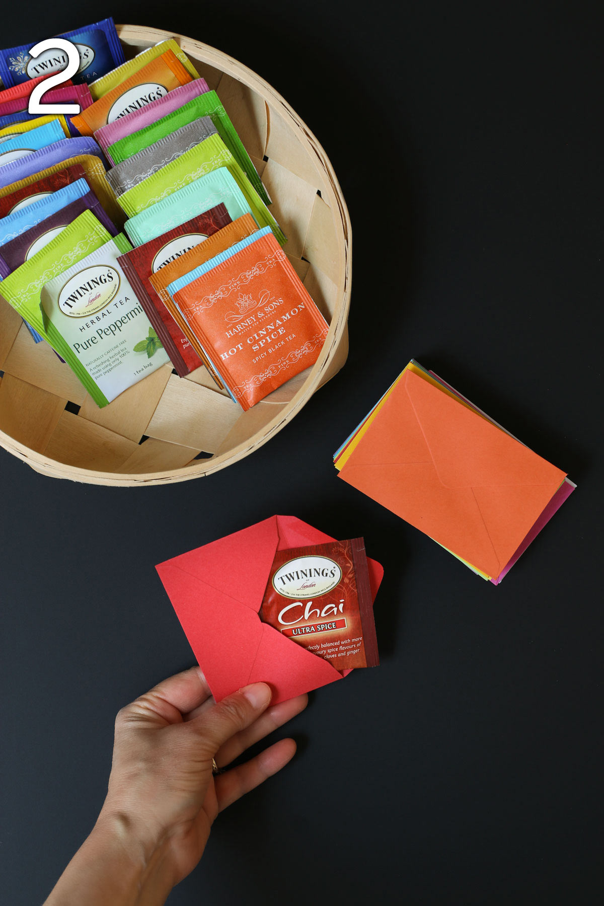 placing a red tea bag into a red envelope with a stack of envelopes and the tea basket nearby.