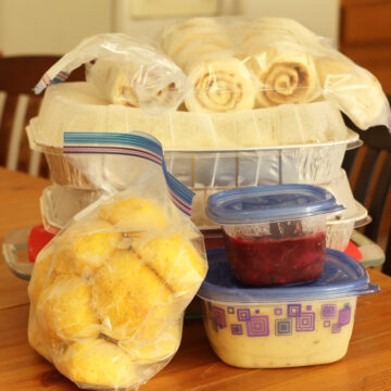 stacks of freezer containers on kitchen table including two bags of rolls.