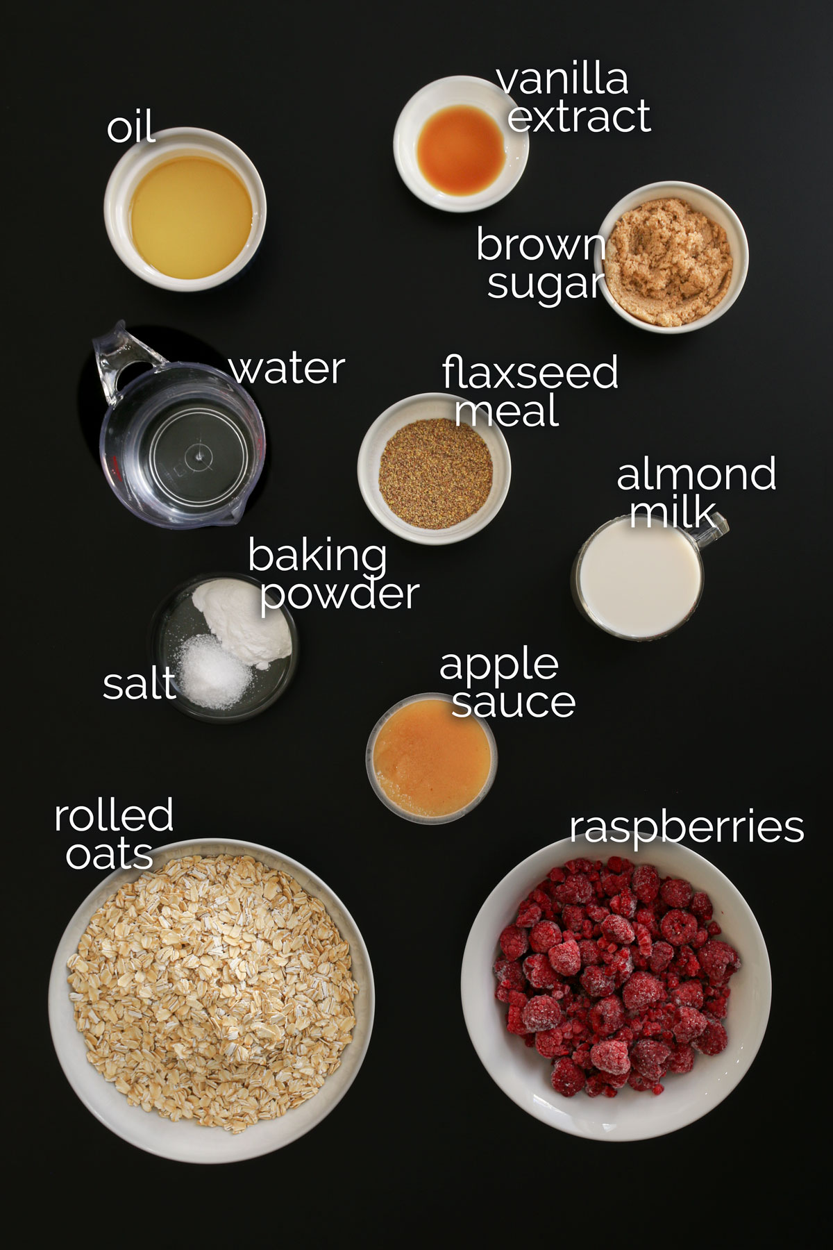 ingredients for vegan baked oatmeal measured and laid out on a black table top.