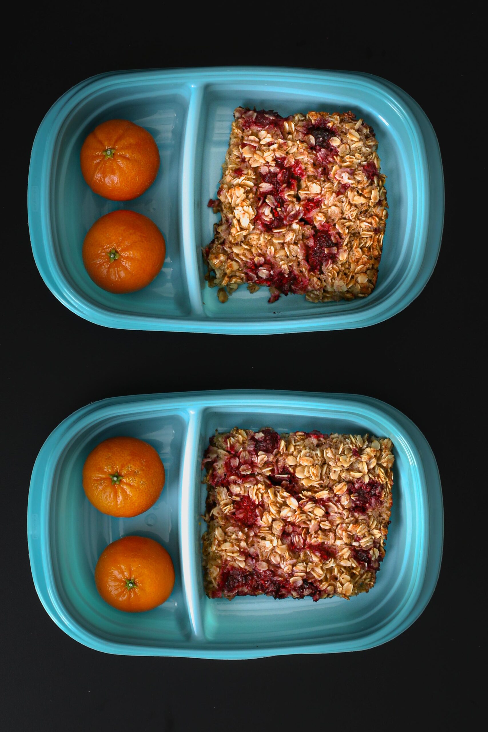 squares of vegan baked oatmeal in teal divided containers with clementines in the other compartment.