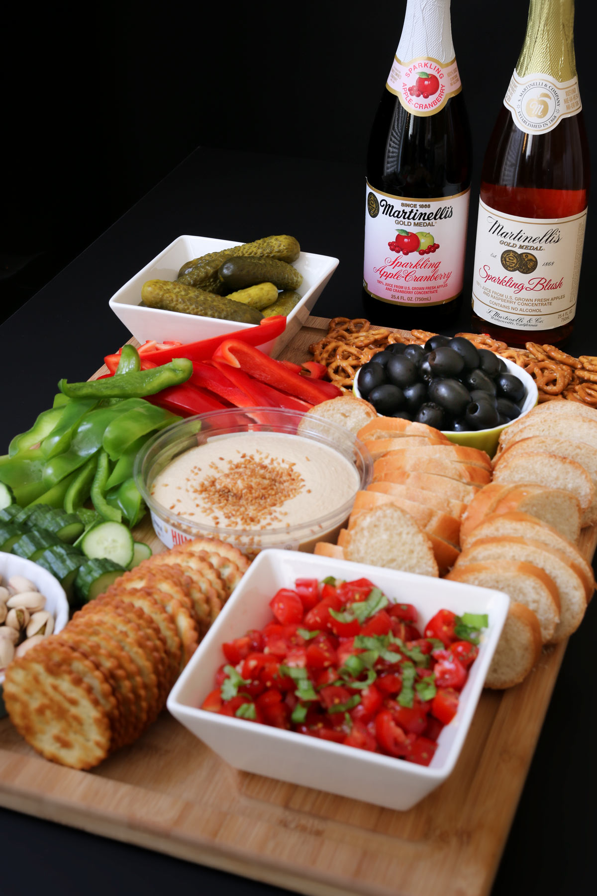 platter of new year's eve appetizers on wooden board with two bottles of cider in the background.