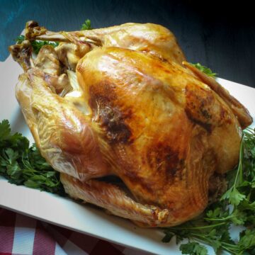 roast turkey on a white platter surrounded by parsley.