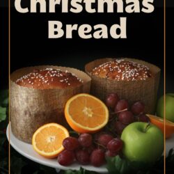 two rounds of christmas bread on a cake stand with an assortment of winter fruit, against a black background with a text overlay.