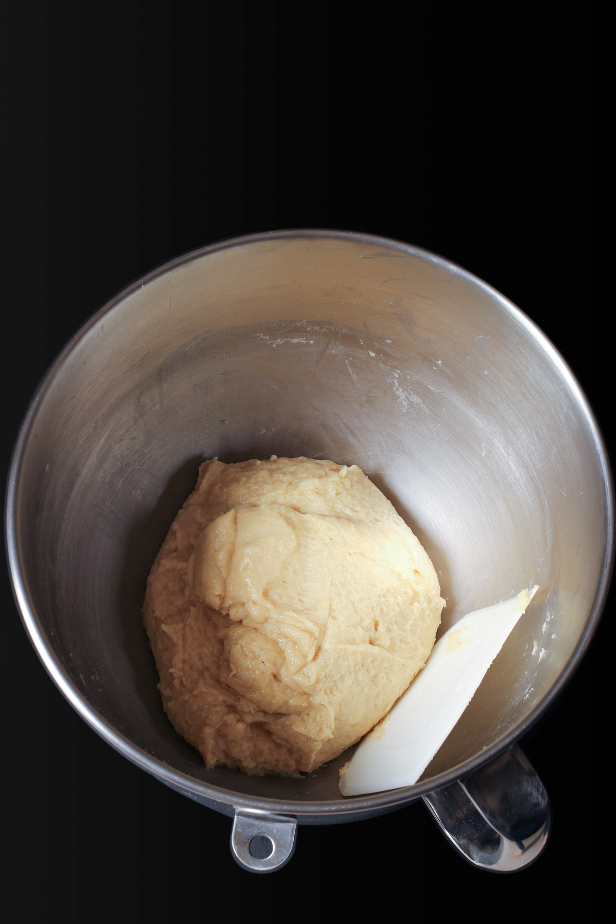 scraping the sides of the bowl around the dough ball to make a firm ball.