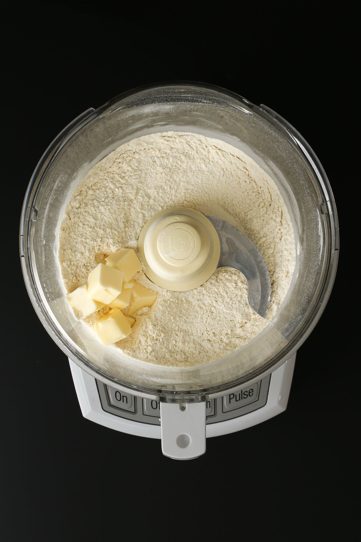 adding butter to the food processor bowl.