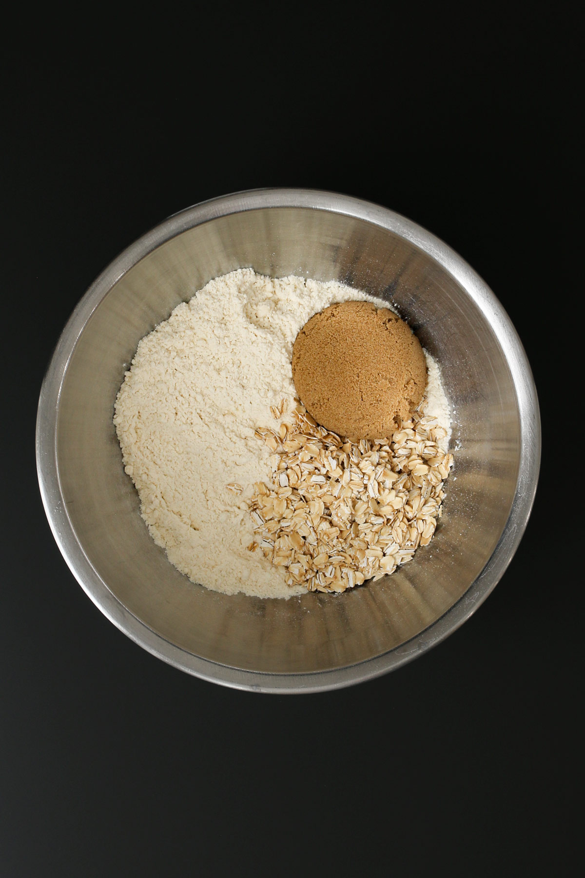 dry mixture in metal bowl with sugar and oats added.
