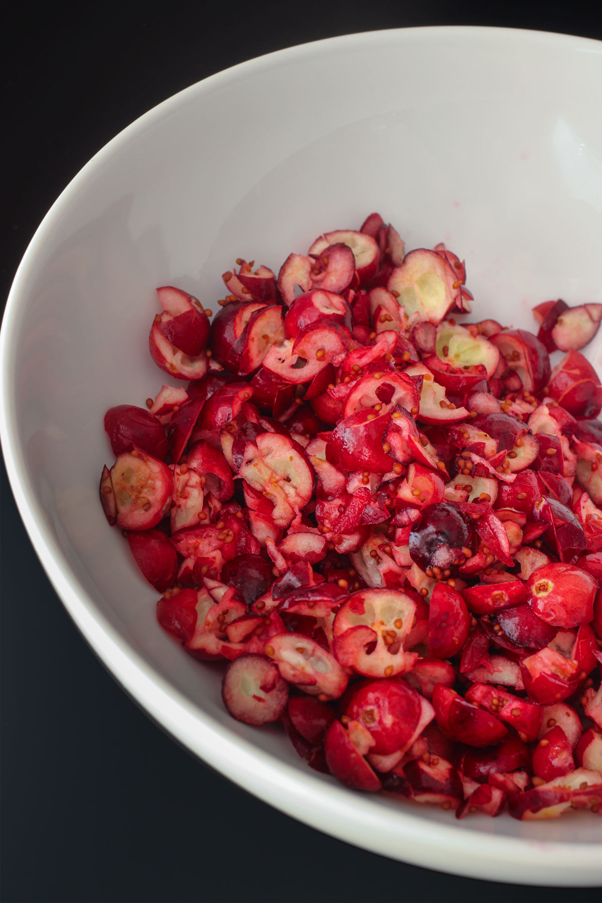 coarsely chopped cranberries in white bowl.