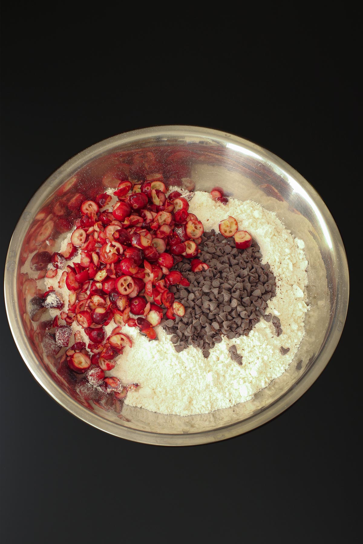 chopped cranberries and chocolate chips added to flour mixture in large metal bowl.