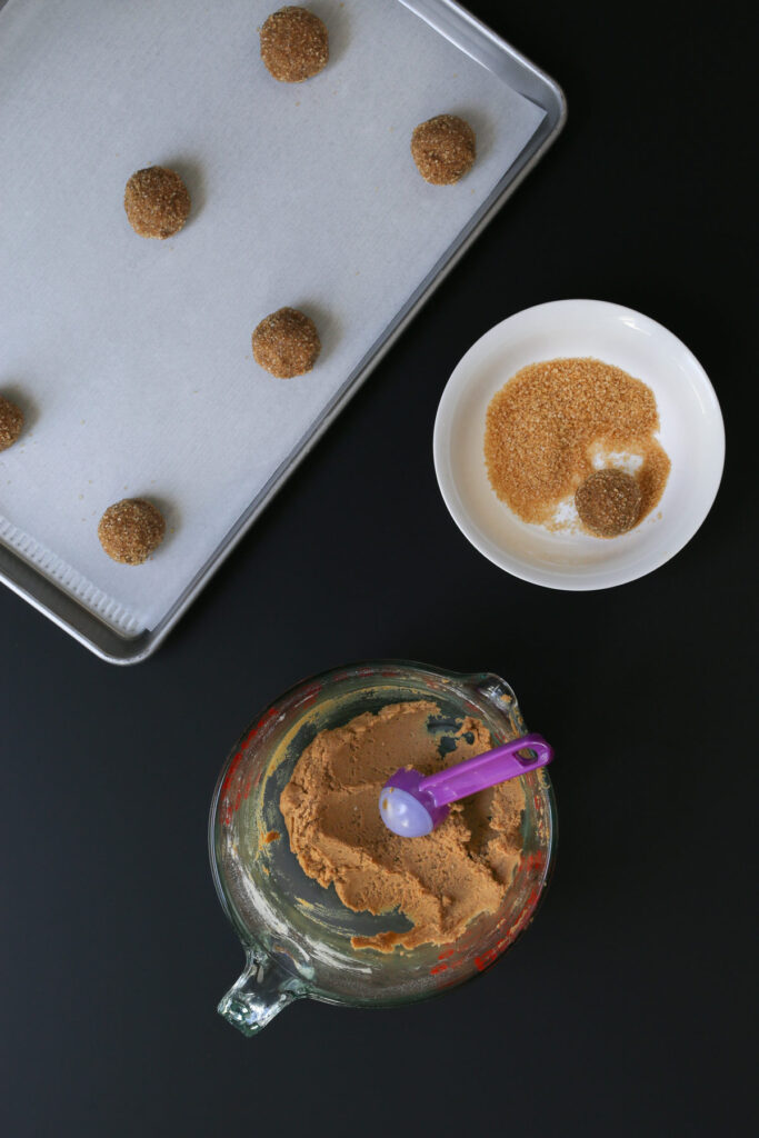 rolling dough balls in sugar and placing on tray.