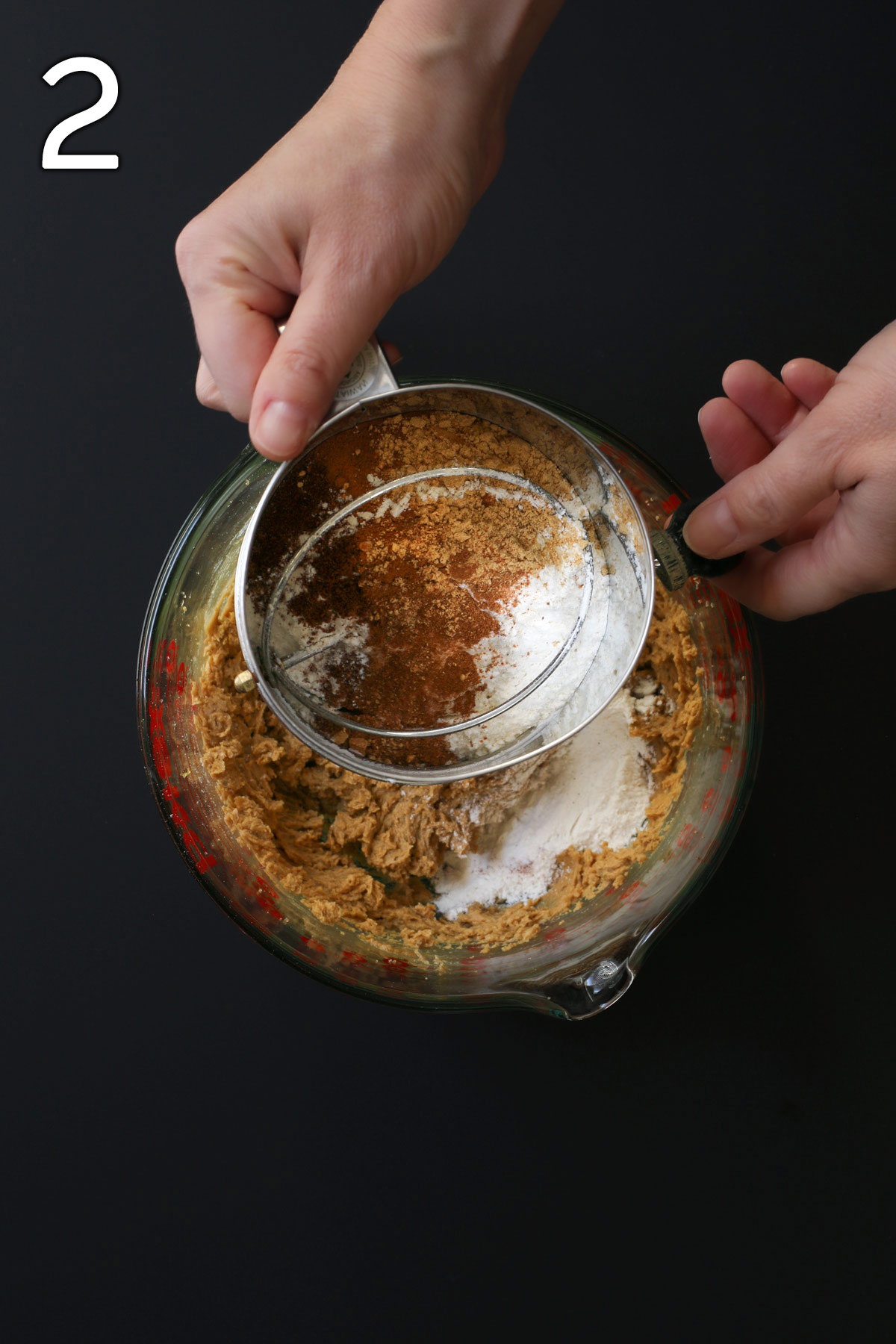 holding the sifter of dry ingredients over the pyrex bowl.