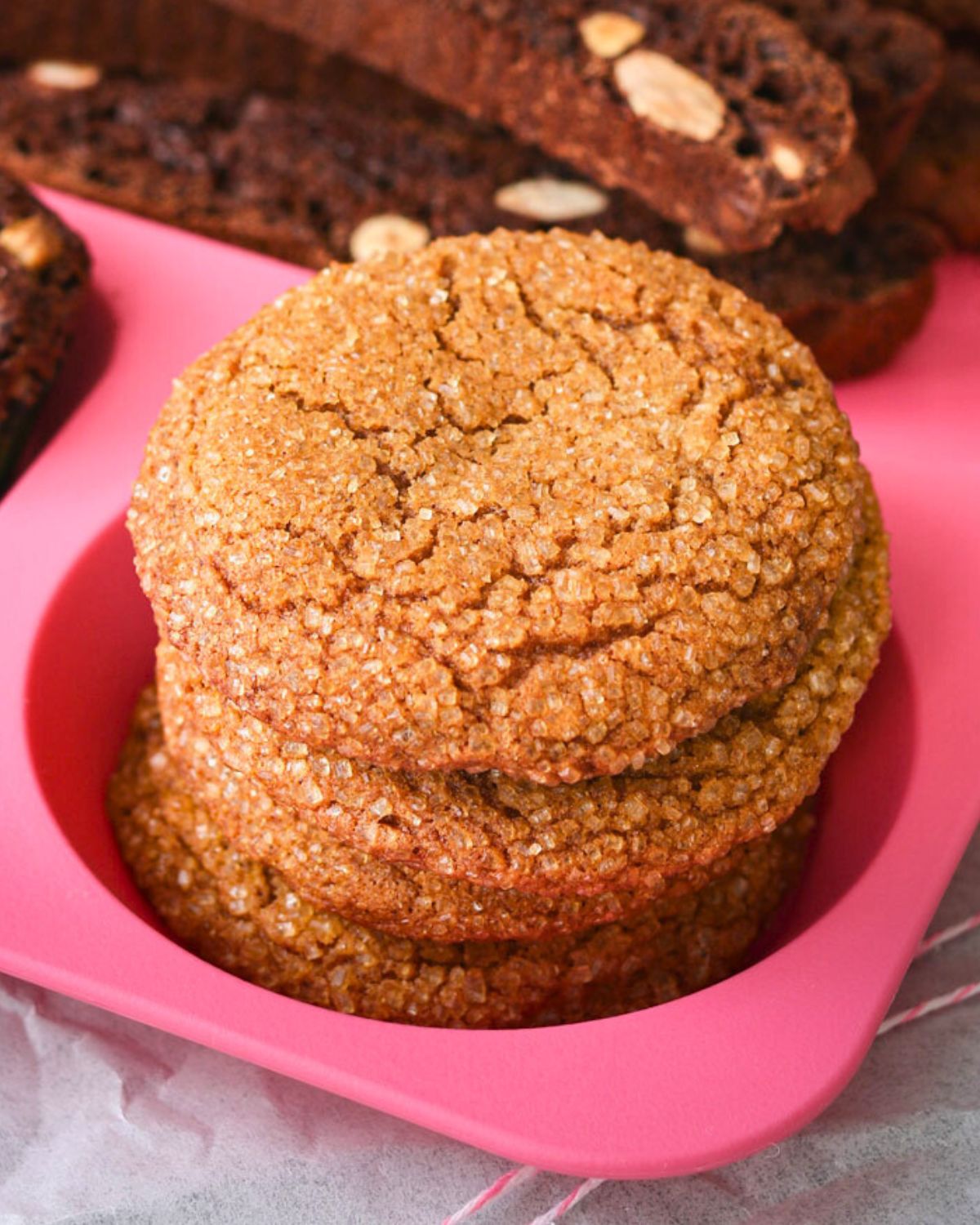close up of stacked molasses crinkles on pink tray.