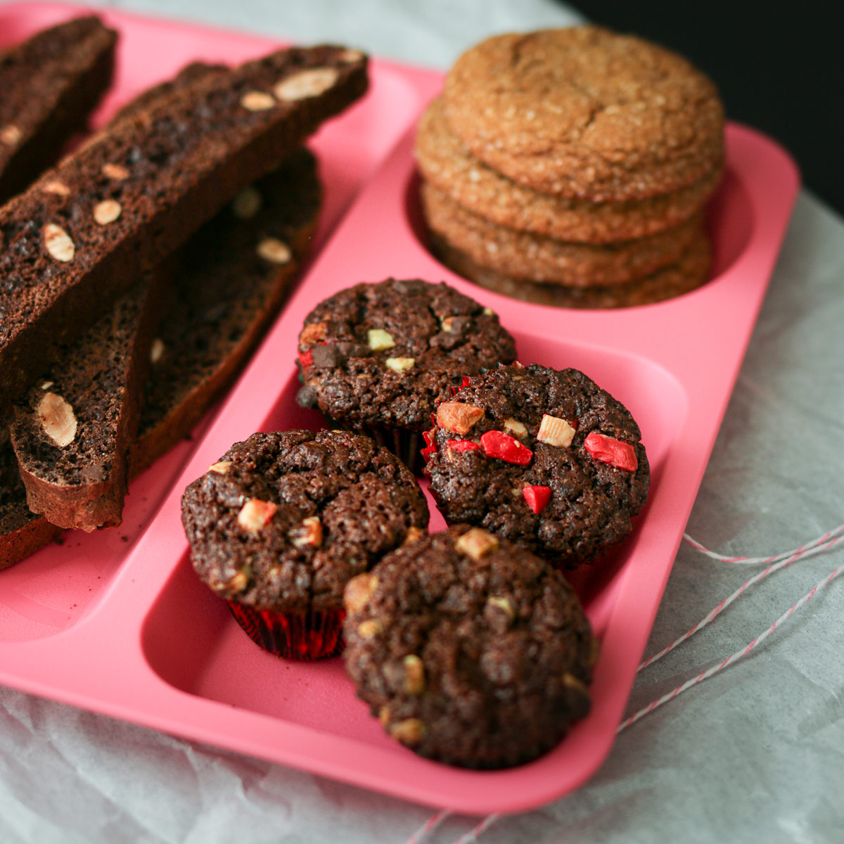 assortment of cookies on a pink divided tray with four peppermint brownie bites in front section.