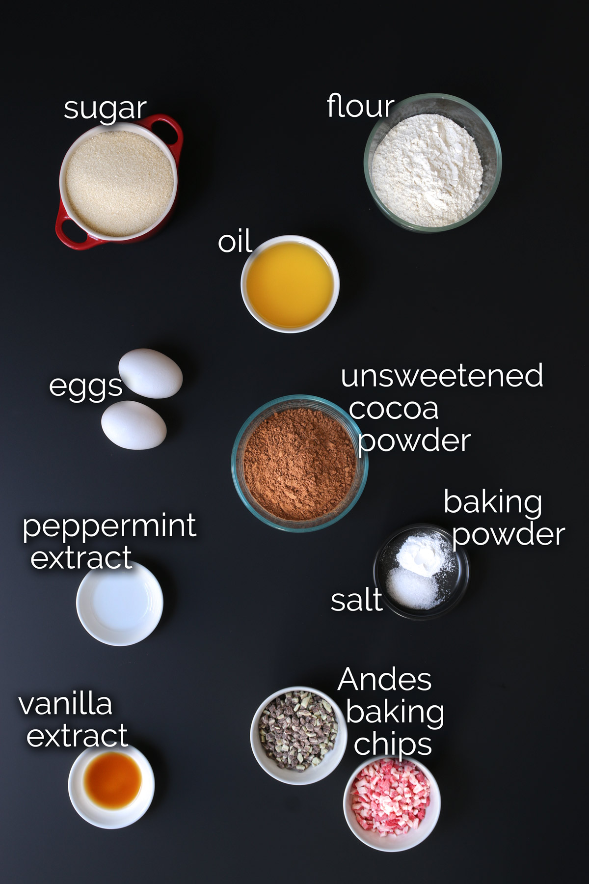 ingredients for brownie bites measured and laid out on a black table top.