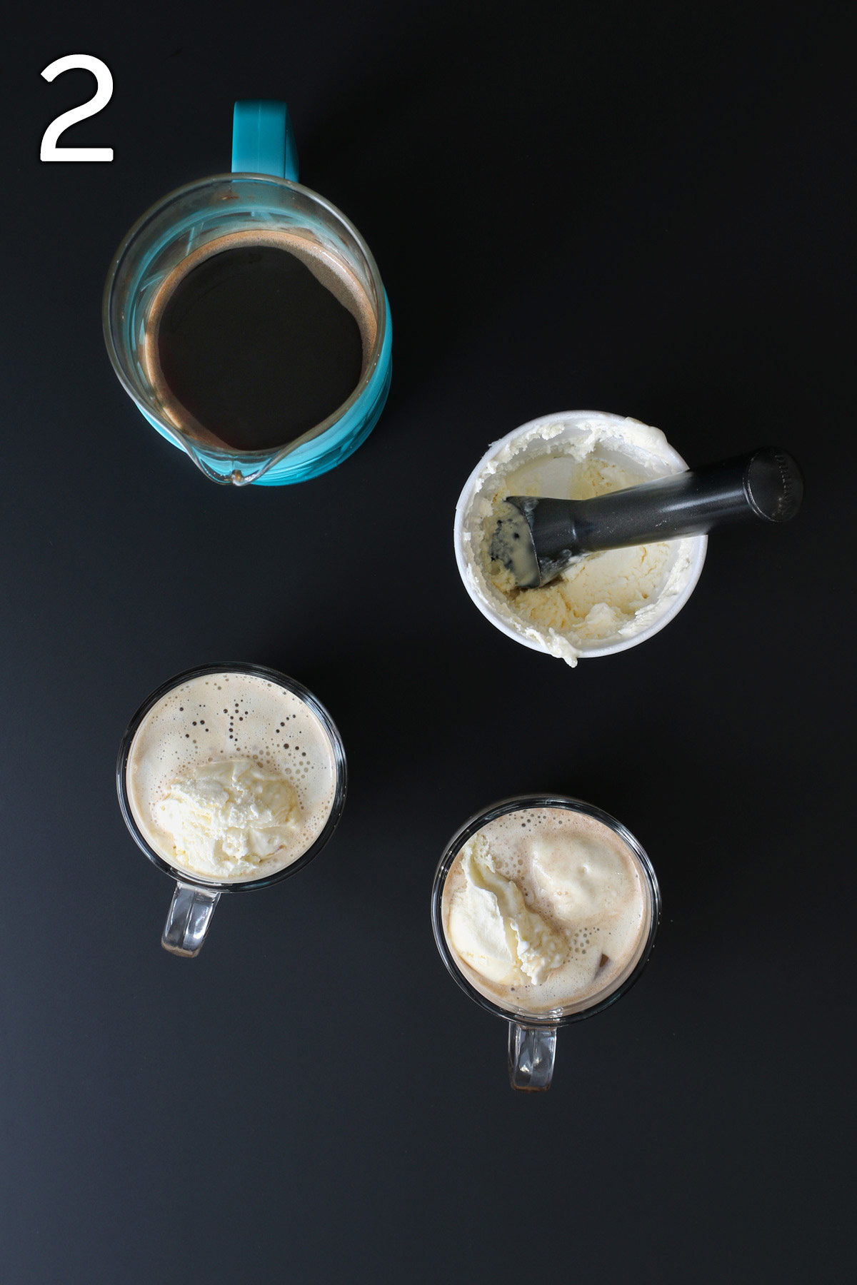 scoops of ice cream are added to mugs of coffee, French press is nearby with a pint of ice cream with a scoop in it.