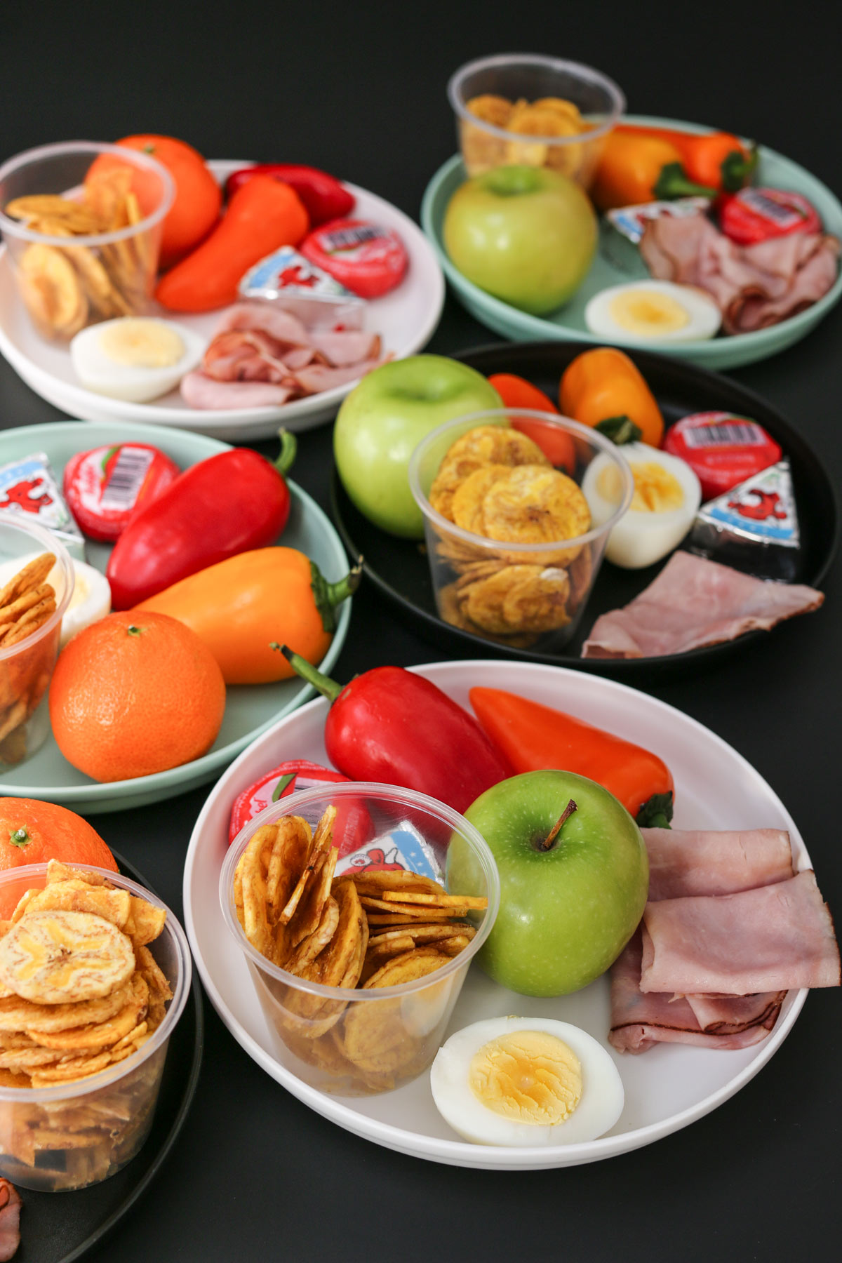 assortment of colored plates with ingredients for mini charcuterie boards.