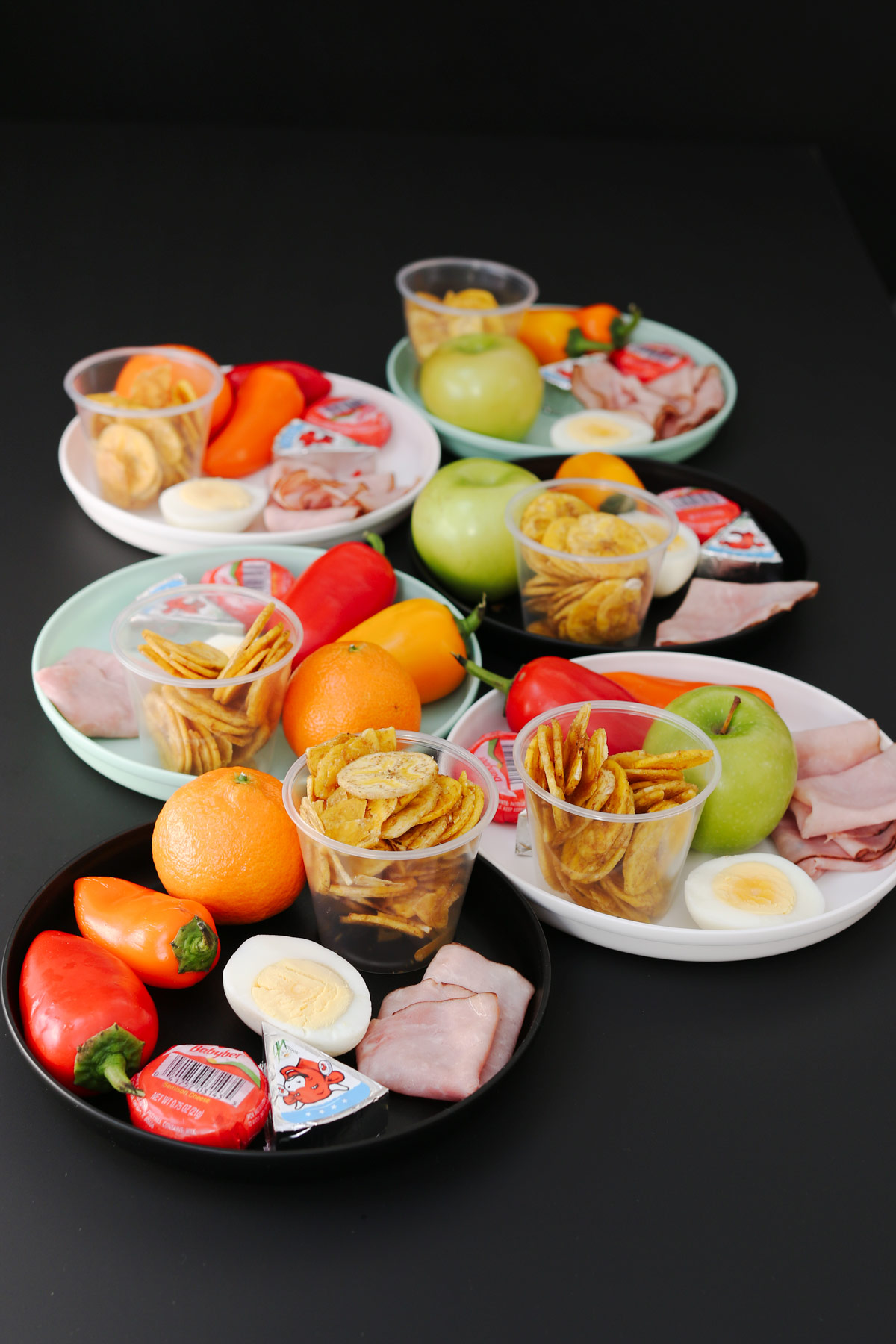 a collection of snack lunches prepared on plates of different colors.