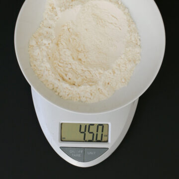 bowl of flour on scale weighing out 4.5 ounces of flour.