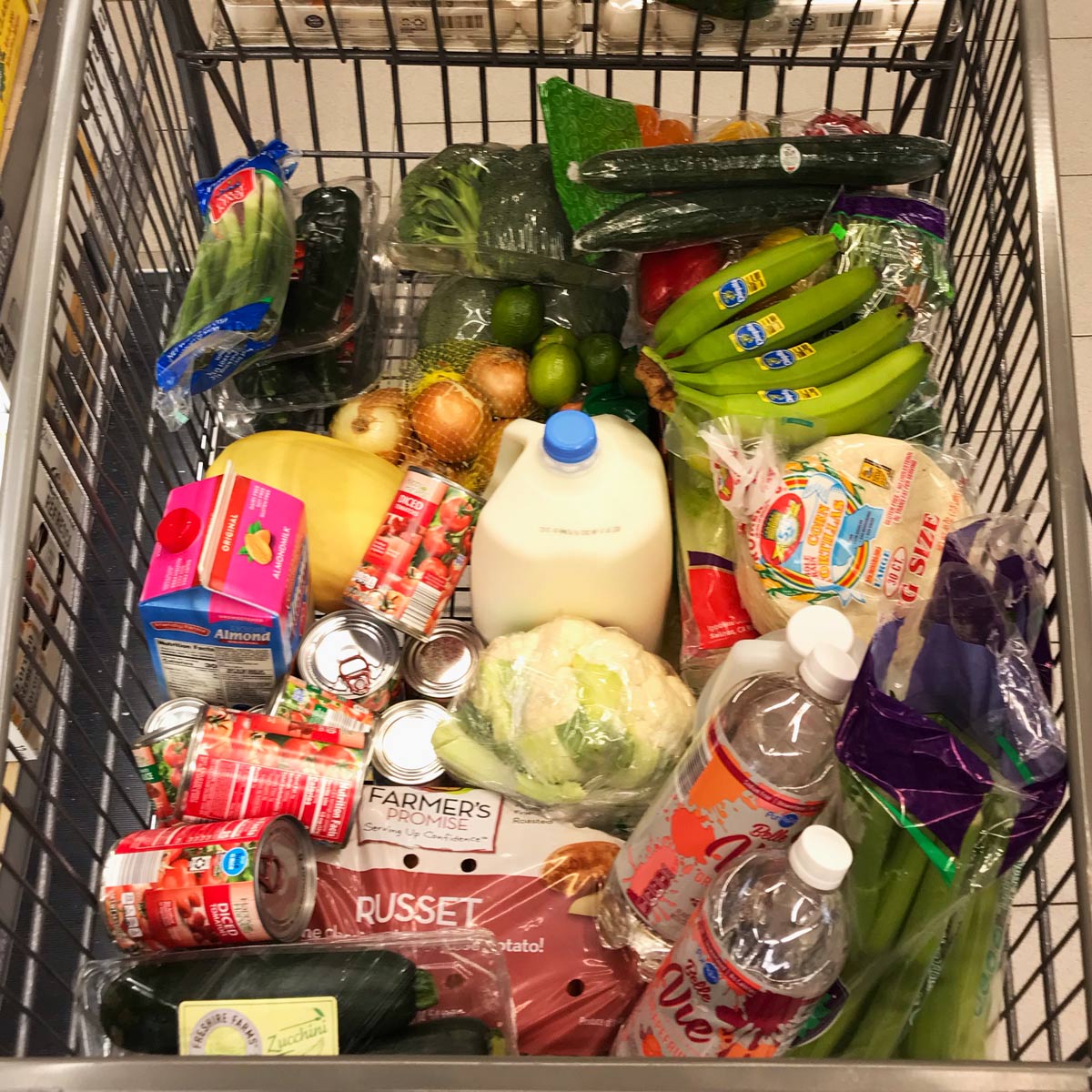 ALDI cart full of mostly fresh produce with some canned goods and milk added.