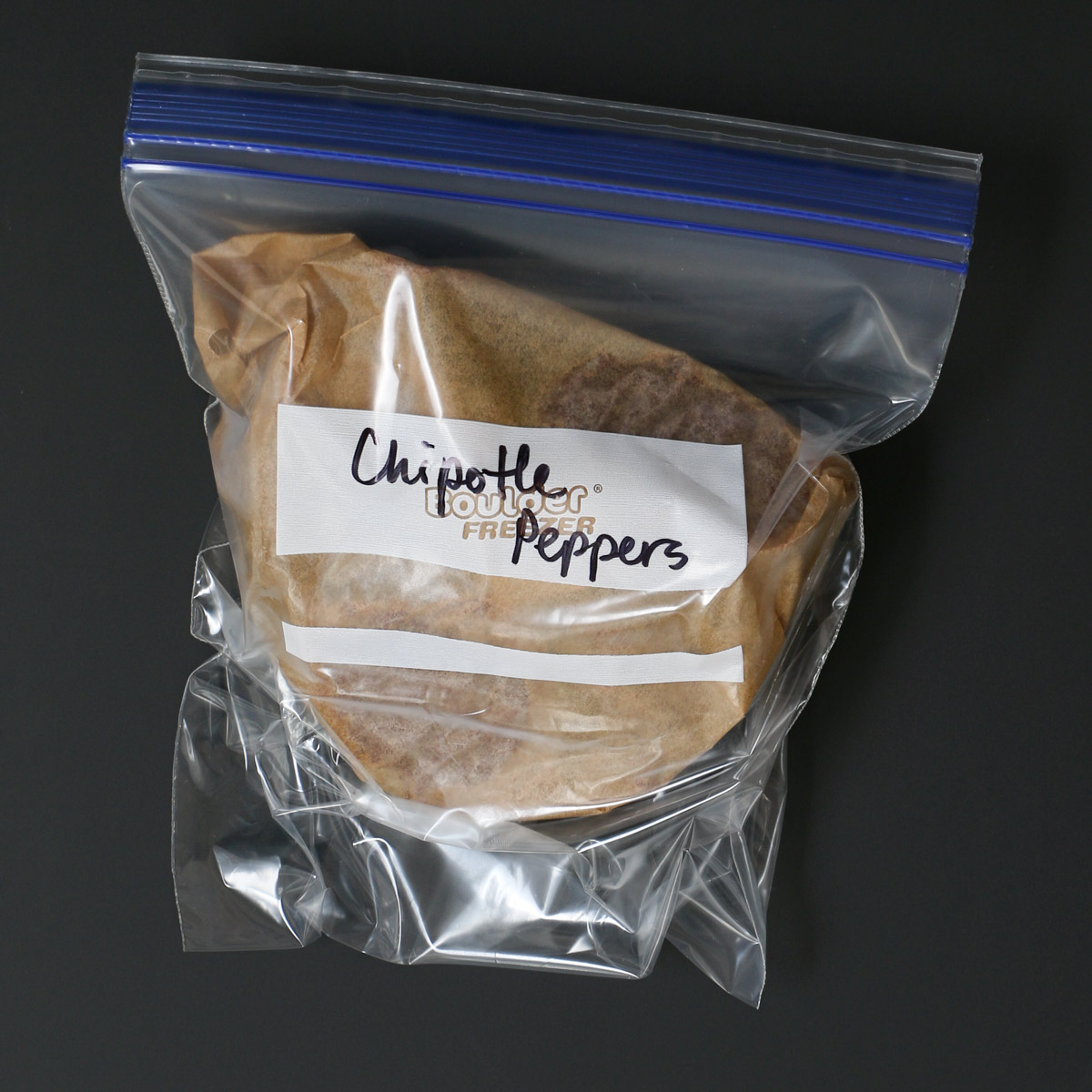 bagged and frozen chipotle peppers on a black table.