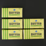 five pound boxes of butter laid out on a black table.