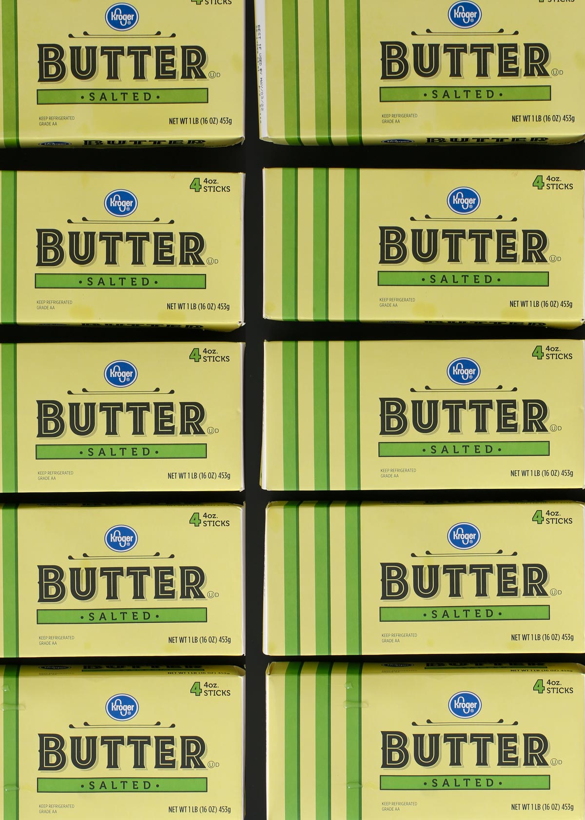 array of yellow and green boxes of kroger butter on a black table.