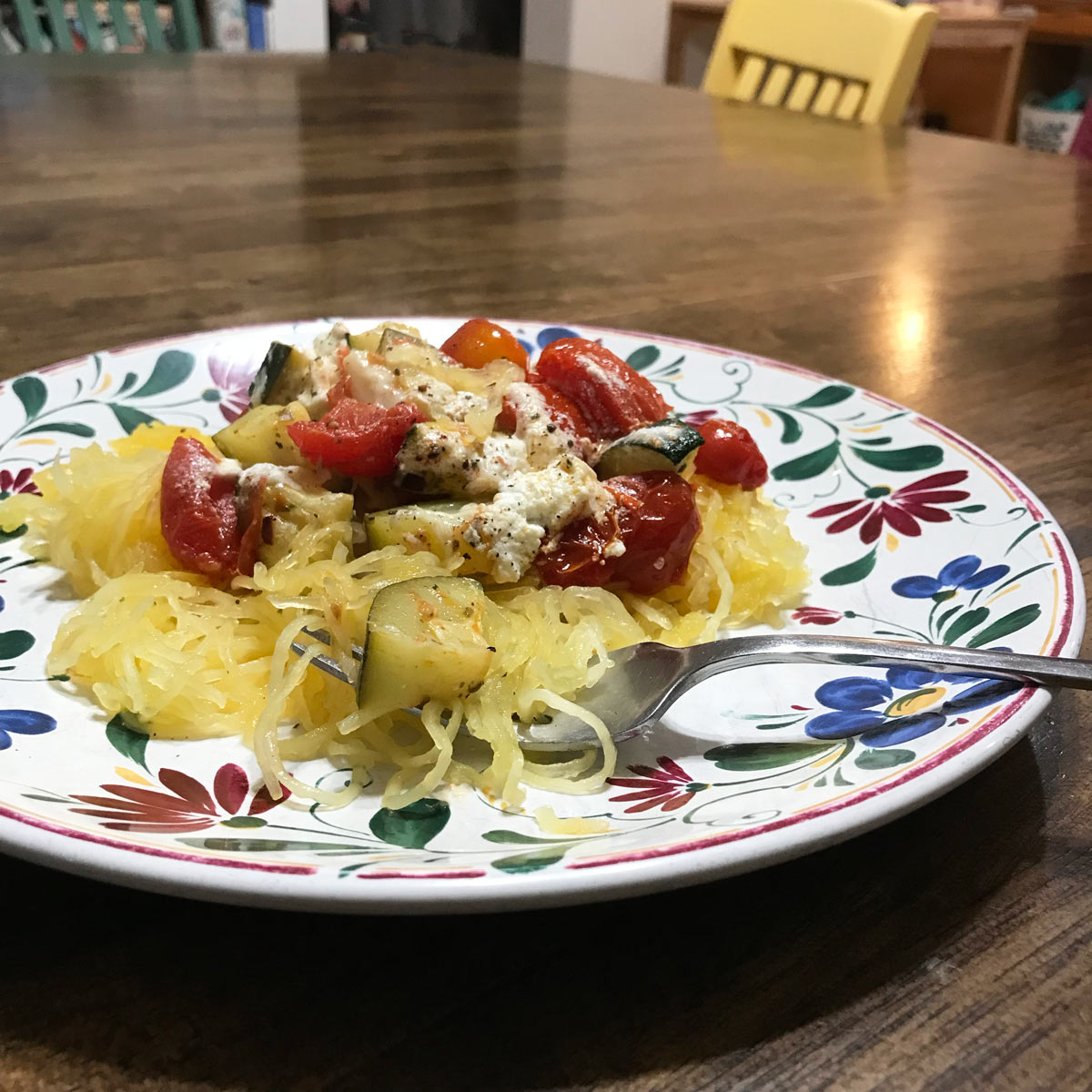 flowered plate with roast vegetables and goat cheese on spaghetti squash.