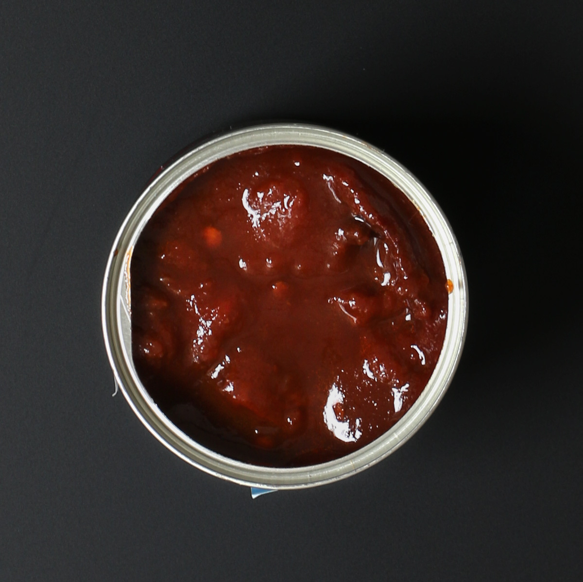 overhead shot of an open can of chipotle peppers in adobo sauce.