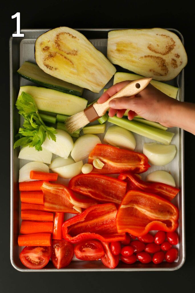 brushing the vegetables on the sheet pan with olive oil.