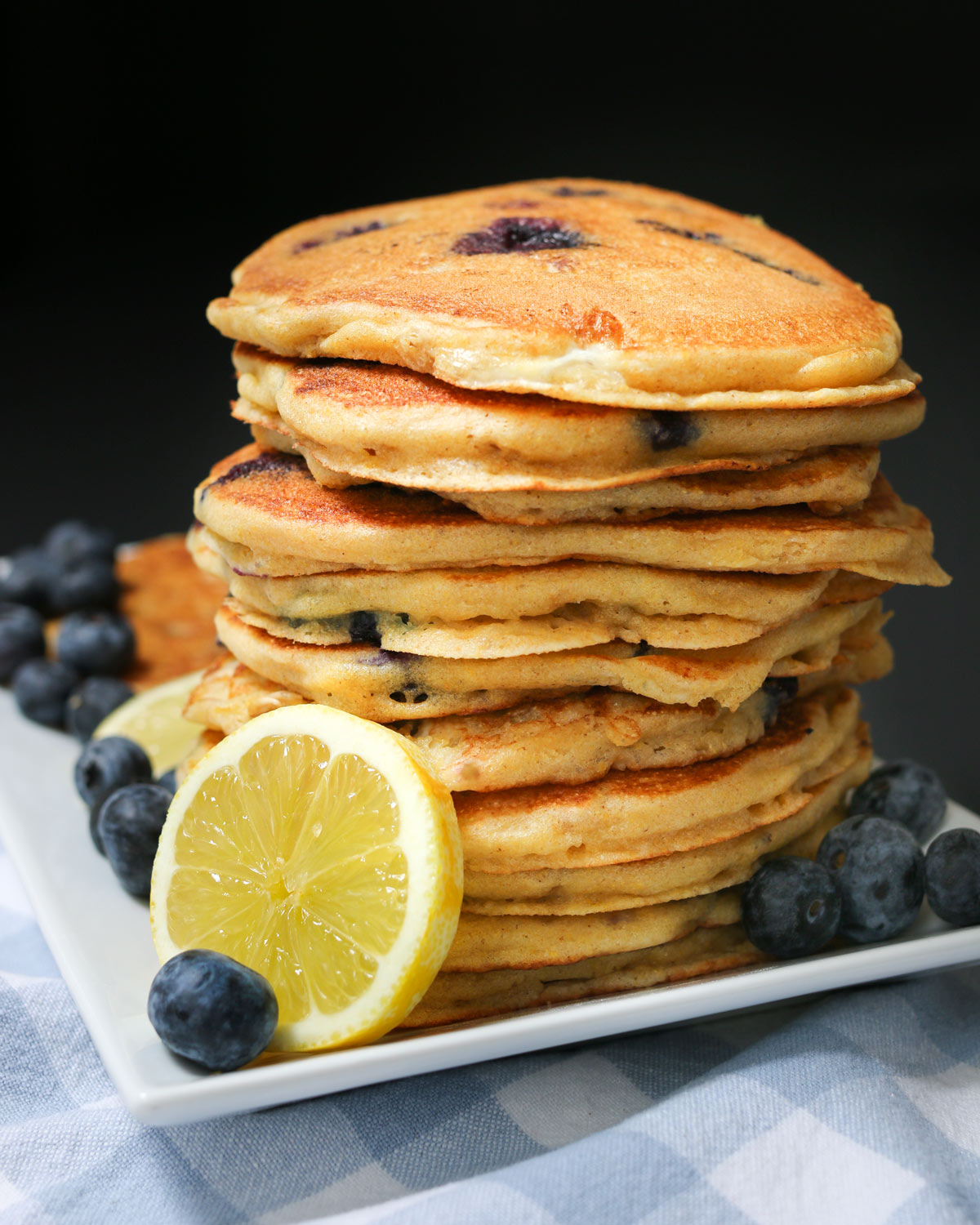 stack of blueberry pancakes with a lemon slice on the platter.