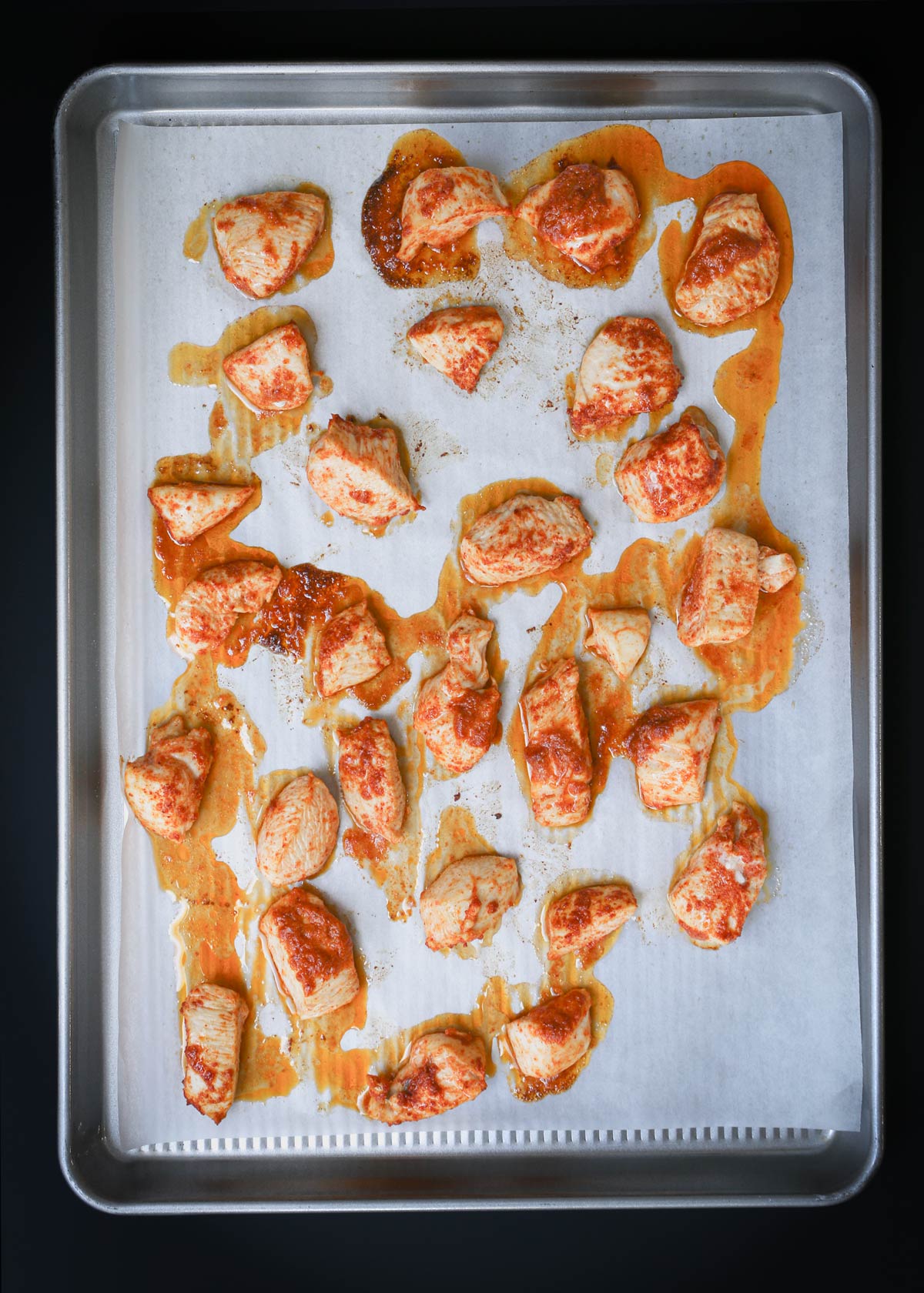 baked buffalo chicken bites on parchment-lined baking sheet.