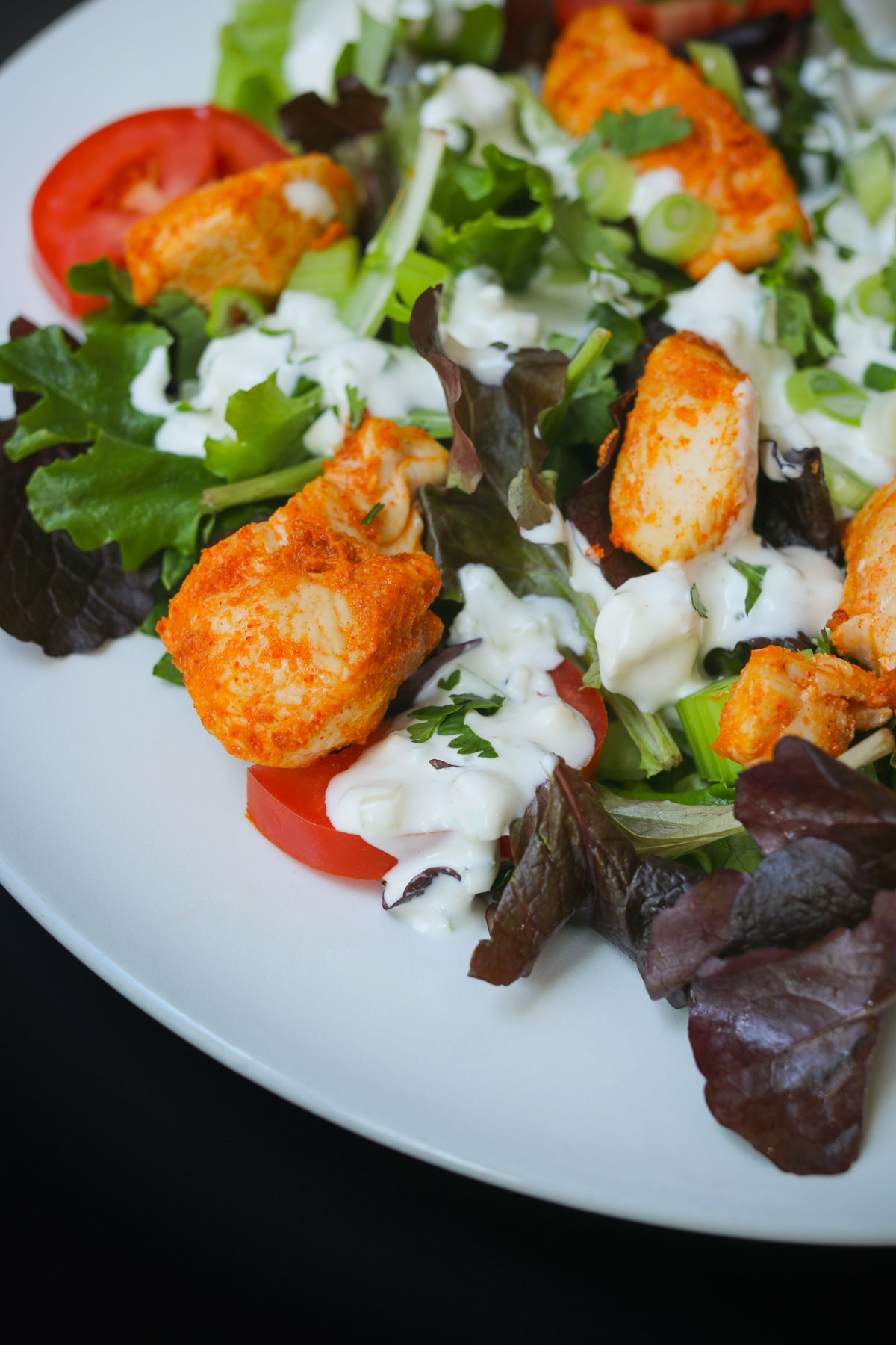 close up of buffalo chicken bite on a salad with blue cheese dressing.