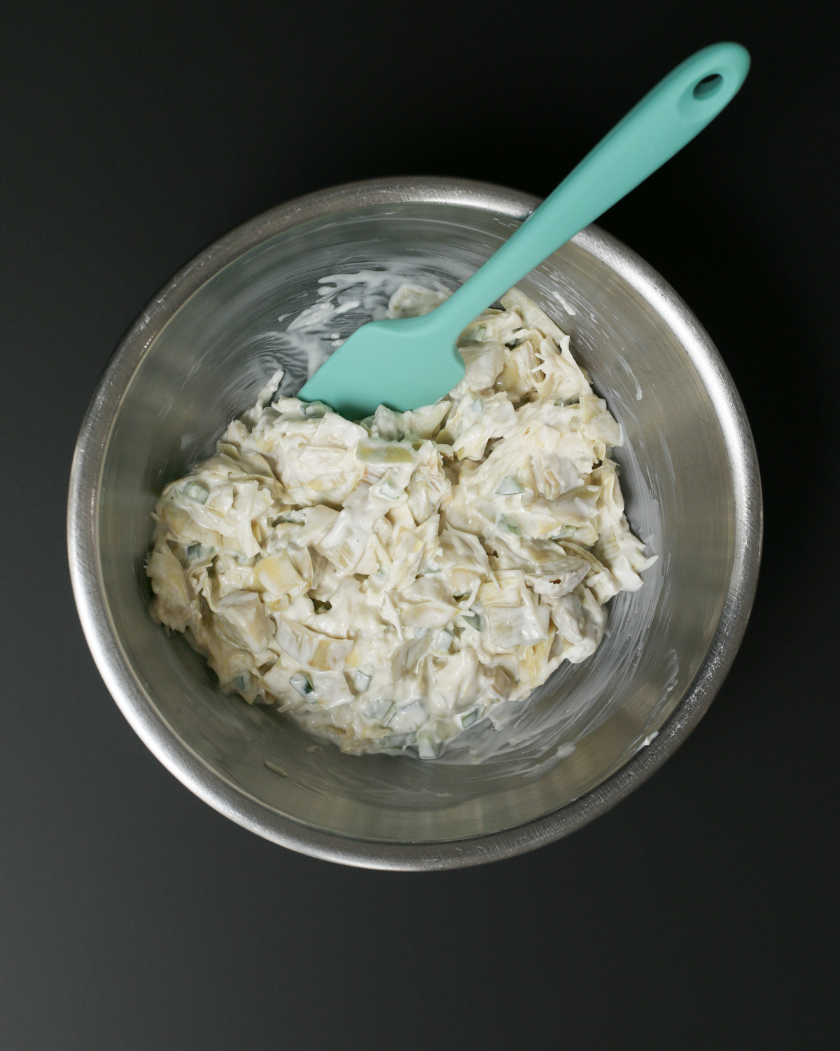 dip ingredients stirred together in the bowl with a teal spatula.