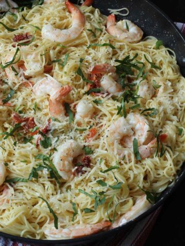 close-up view of skillet full of creamy garlic shrimp pasta topped with fresh parsley.