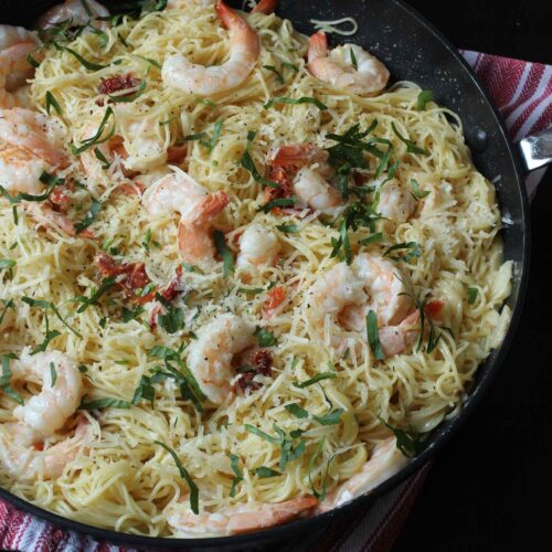 close-up view of skillet full of creamy garlic shrimp pasta topped with fresh parsley.