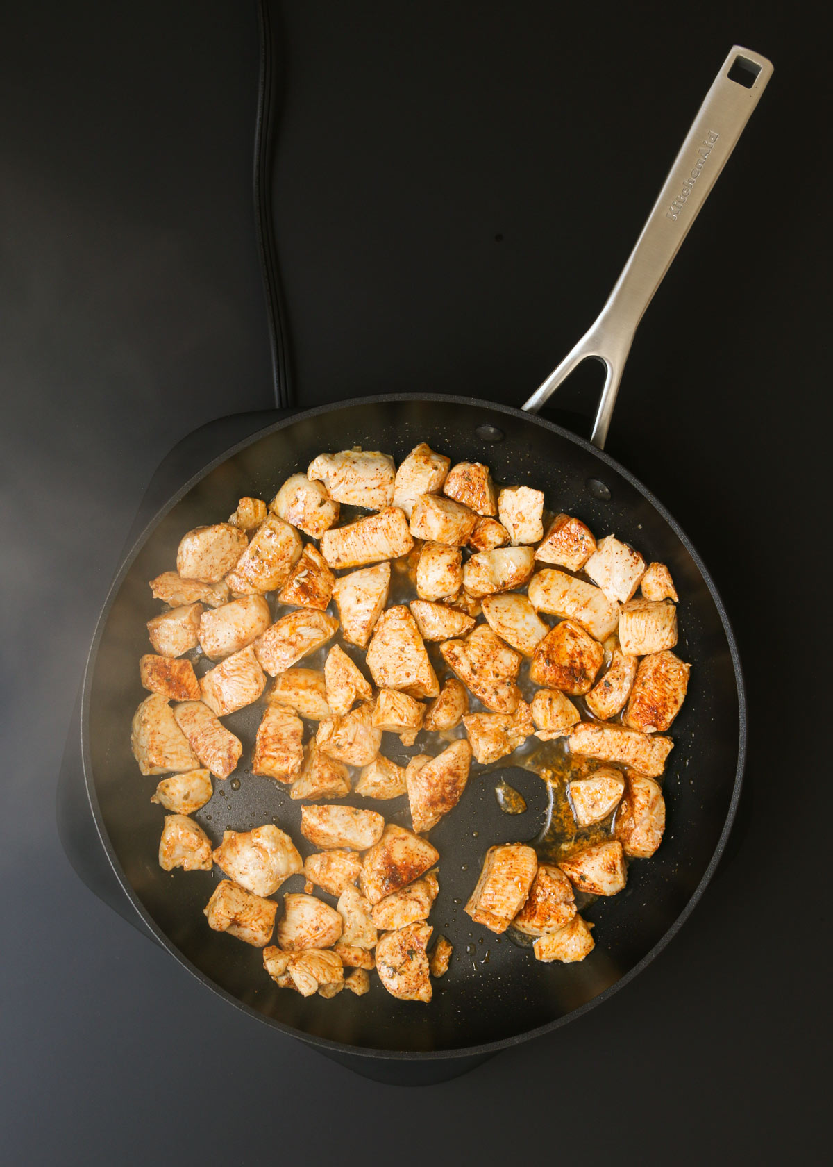 cooked chicken in skillet with steam rising.