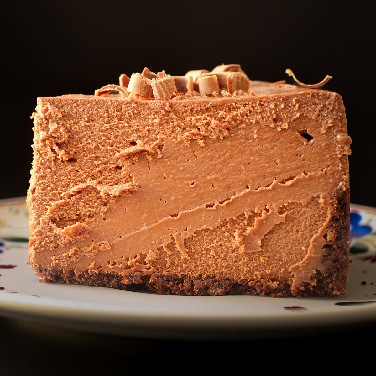 slice of chocolate cheesecake on a flowered plate.