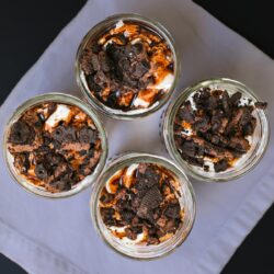 overhead shot of four chocolate parfaits in an array on white napkin.