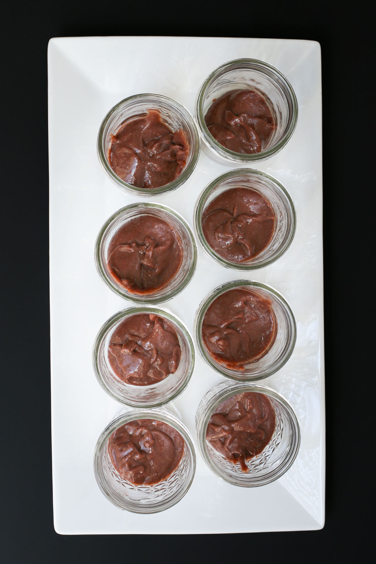 pudding in each of eight half-pint jars on a white tray.