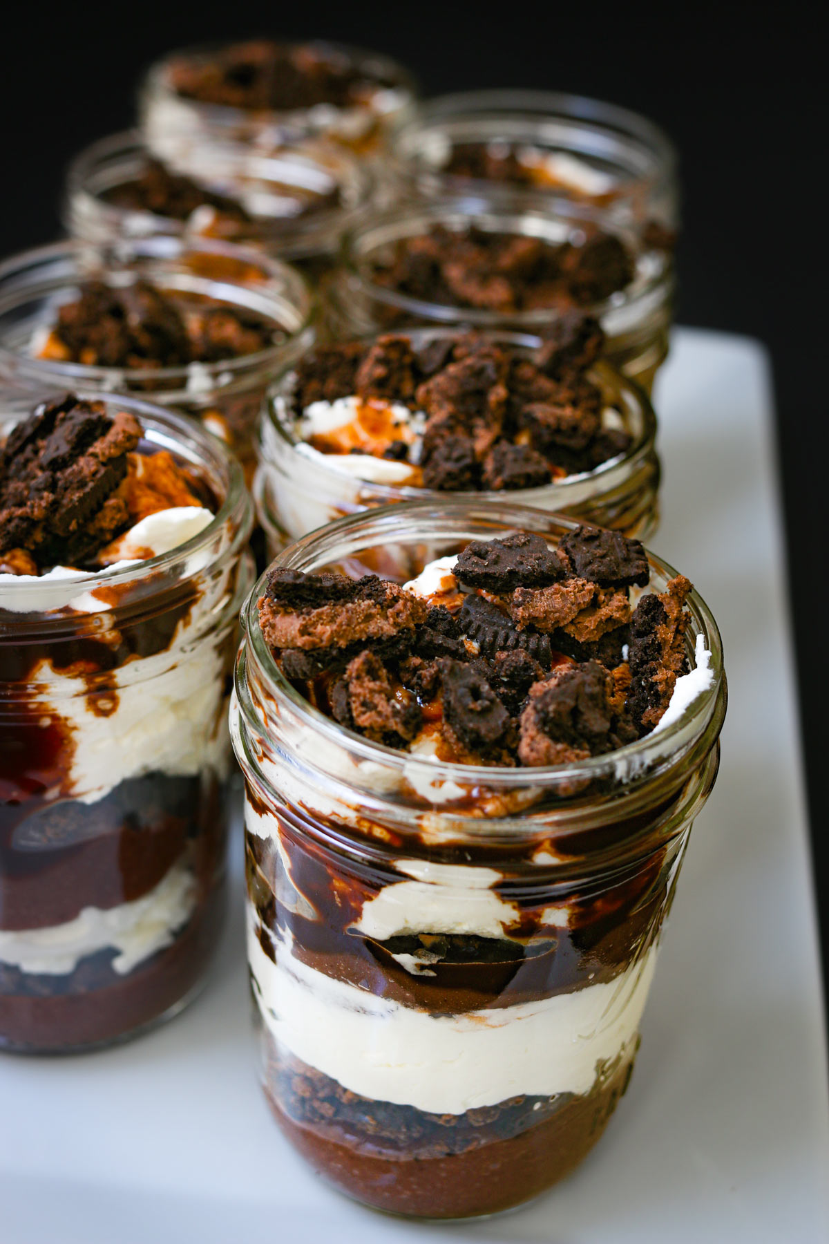 a white tray with jars of chocolate parfaits in rows.