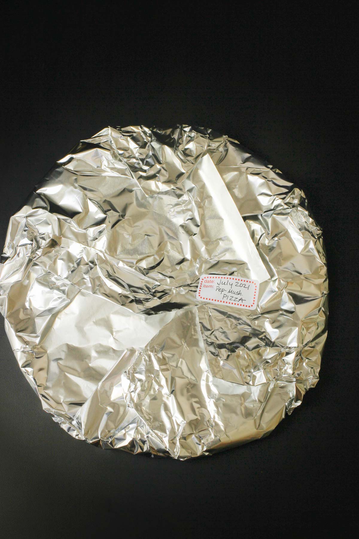 a whole pizza wrapped in foil.