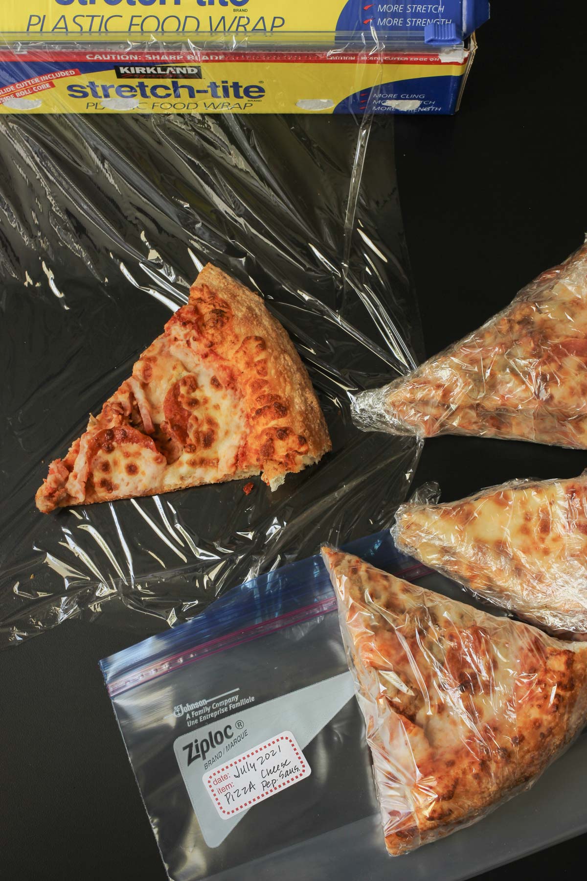 wrapping slices of pizza in plastic wrap.