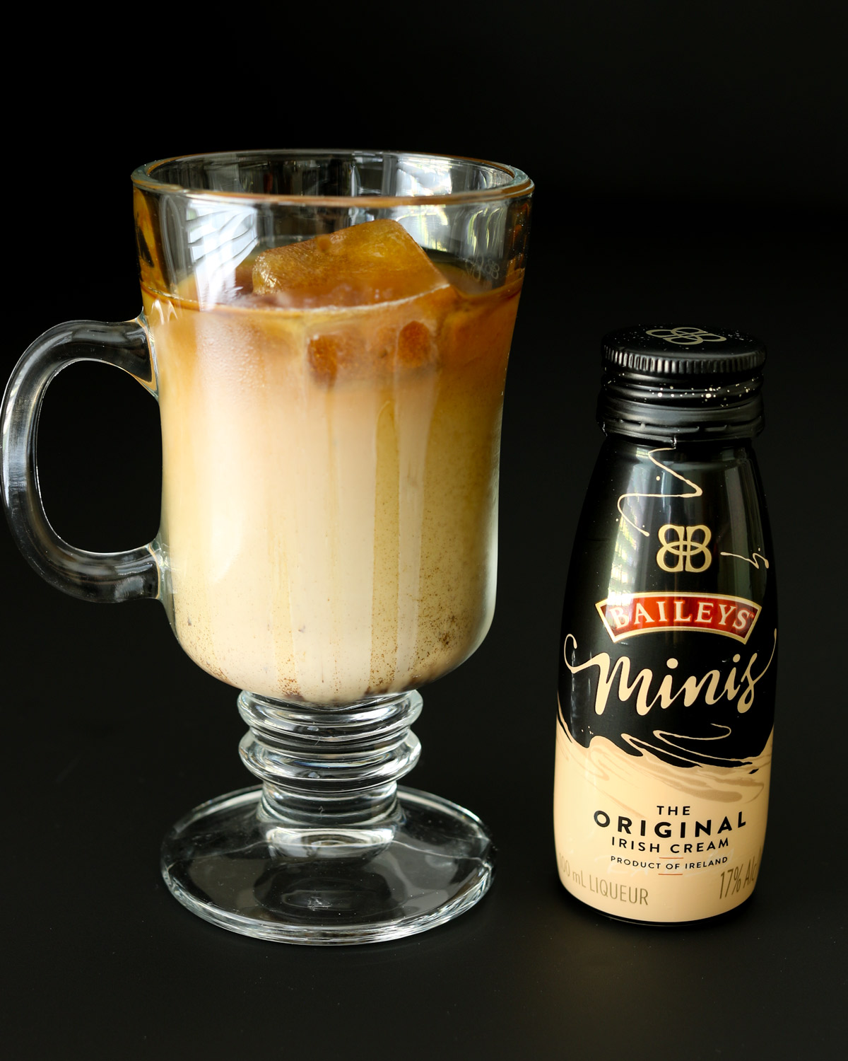 glass of iced coffee next to a mini bottle of baileys.